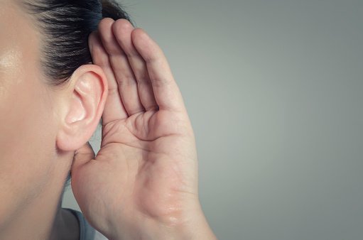 Woman with hand on ear listening for quiet sound or paying attention